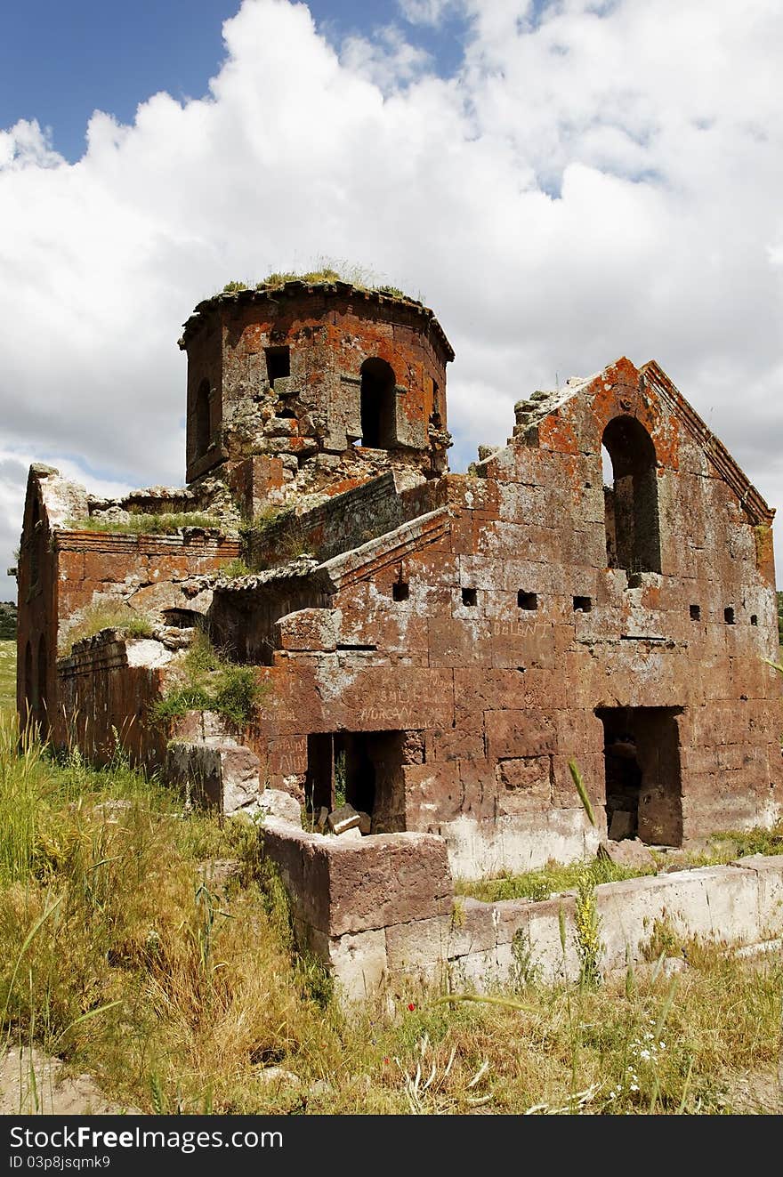 Portrait of Kizil Kilsie with tall grass, Red Church ruins of dilapidated and derelict Church Cappadocia Turkey dating to the 6th century, rustic colors, red limestone, tall grass, crop area and copy space. Portrait of Kizil Kilsie with tall grass, Red Church ruins of dilapidated and derelict Church Cappadocia Turkey dating to the 6th century, rustic colors, red limestone, tall grass, crop area and copy space