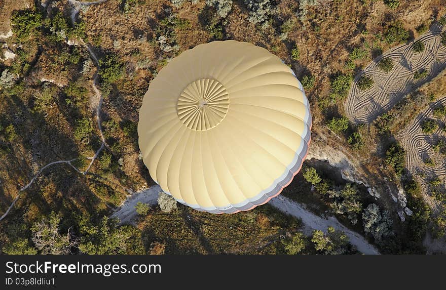 Multi Color banded yellow hot air balloon over the wilderness of Cappadpcia, showing wilderness and farmlands, landscape, crop space, copy space. Multi Color banded yellow hot air balloon over the wilderness of Cappadpcia, showing wilderness and farmlands, landscape, crop space, copy space