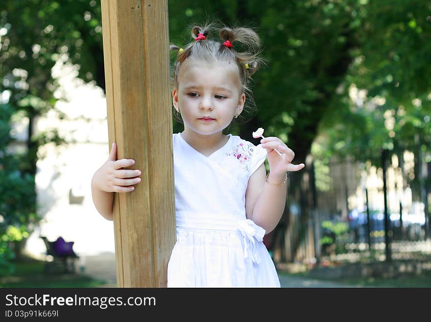 Sad little girl alone in the park looking down. Sad little girl alone in the park looking down