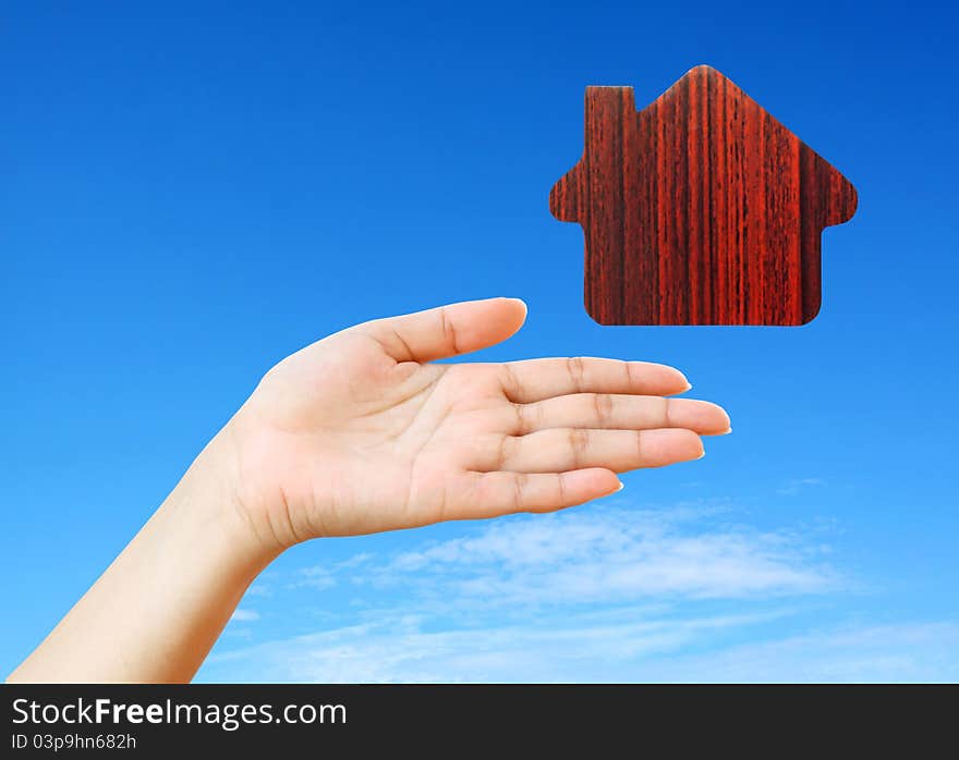 Hand and icon house in the blue sky