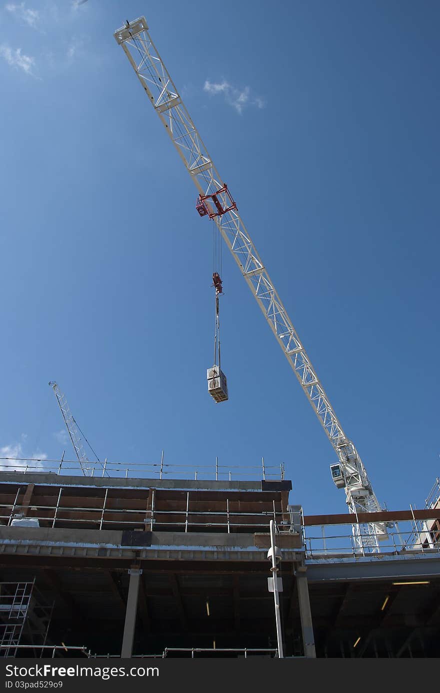 A White Tower Crane lifting an air conditioning unit on a consruction site. A White Tower Crane lifting an air conditioning unit on a consruction site