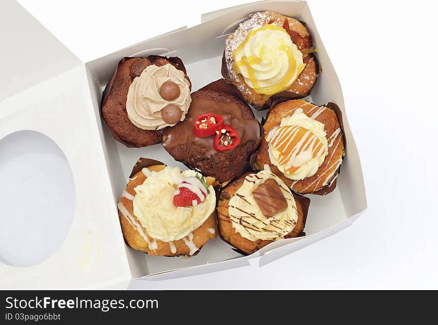 Cupcakes of different flavours in a freshly opened box slightly squashed. Cupcakes of different flavours in a freshly opened box slightly squashed