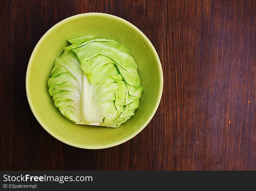 Image of white cabbage in a deep plate over wooden background