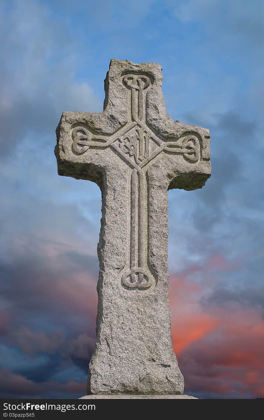 Irish granite celtic cross with traditional carved designs against a colourful stormy sky. Irish granite celtic cross with traditional carved designs against a colourful stormy sky