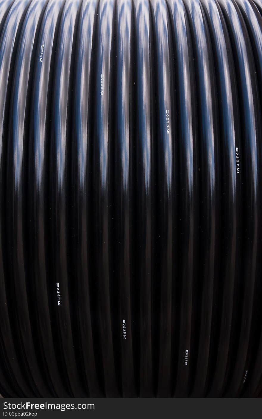 Black electric cable rolled in reel pattern vertical. Black electric cable rolled in reel pattern vertical