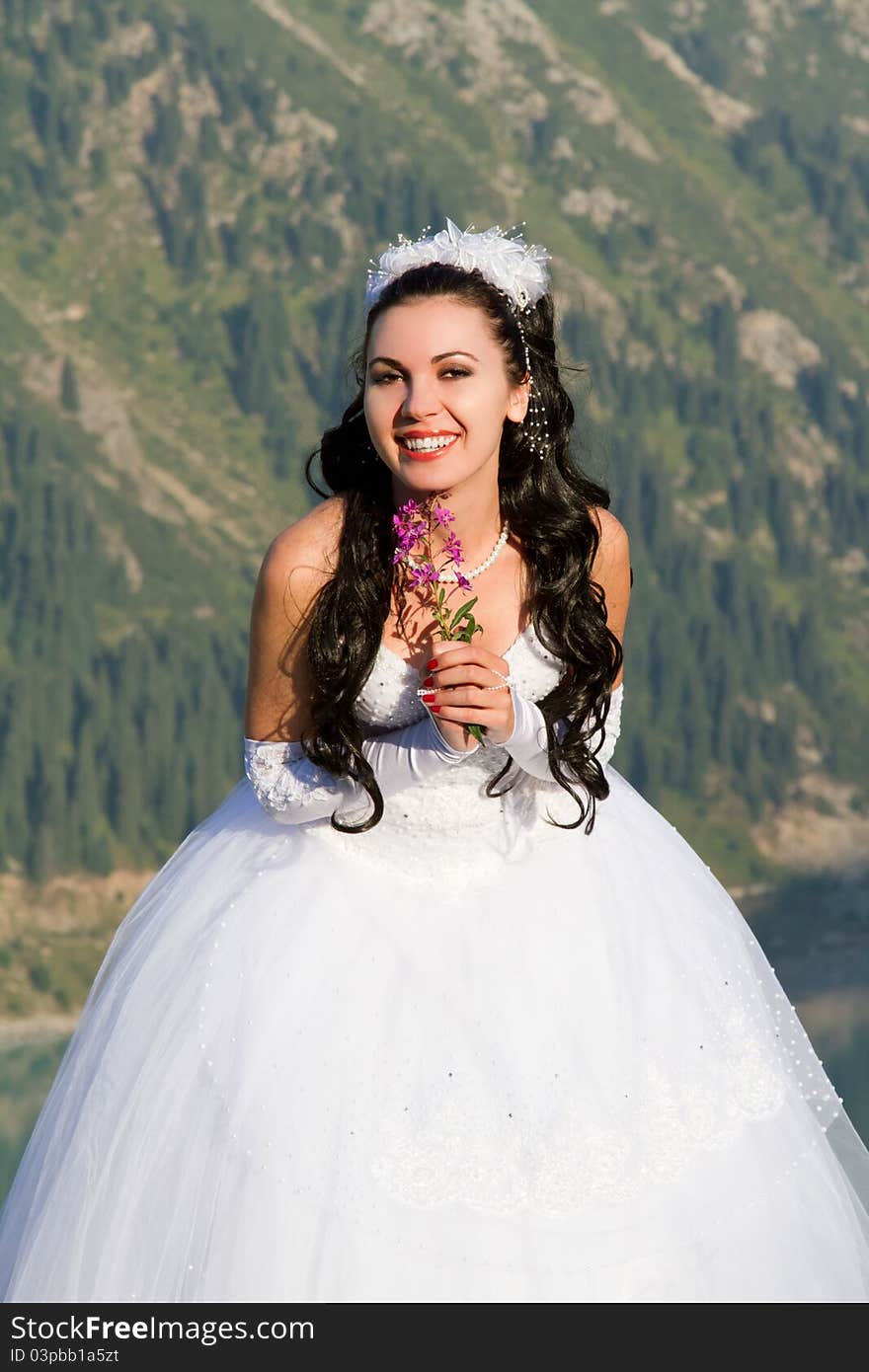 Smiling bride with flowers in the mountains