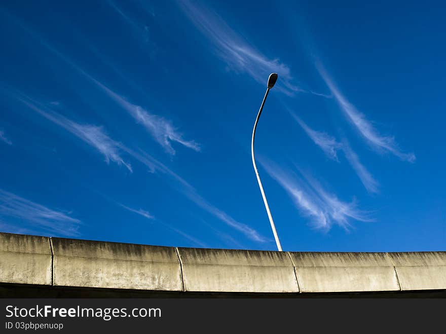 Crazy clouds on a blue sky over a bridge with a light post