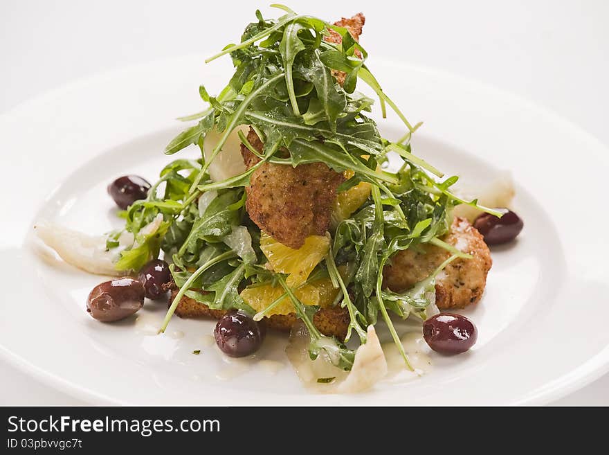 Crumbed chicken with rocket,onions,olives and oranges on a plate