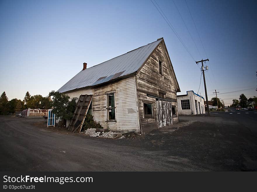 An aging and abandoned building sits in a nearly empty lot in the evening hours.