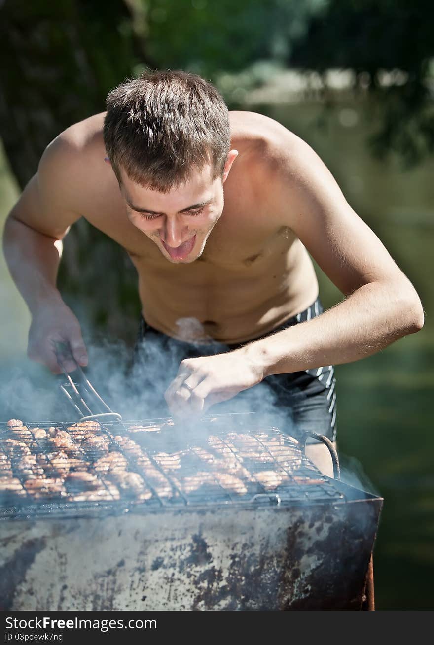 Young man preparing barbecue outdoors. Young man preparing barbecue outdoors