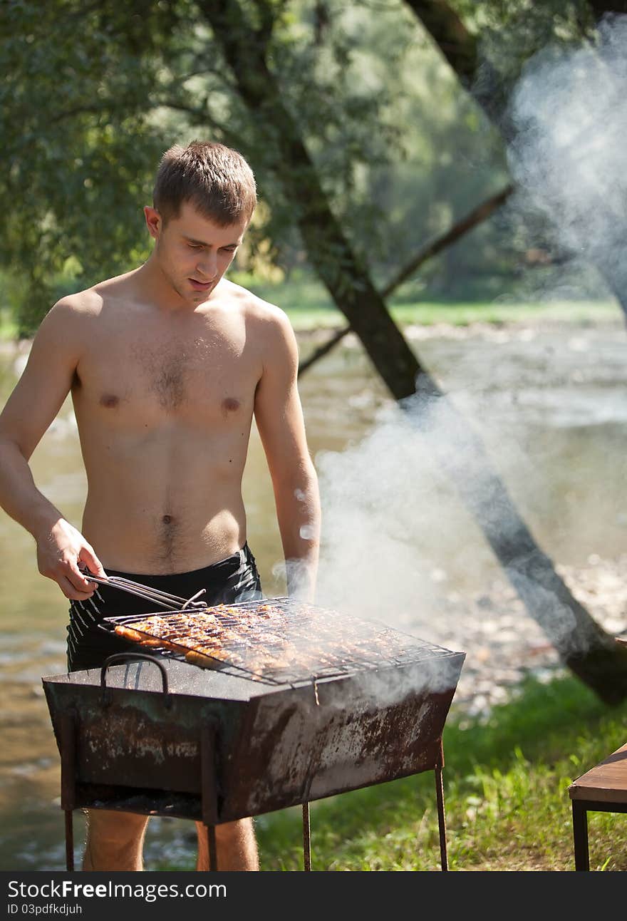 Young man preparing barbecue outdoors. Young man preparing barbecue outdoors