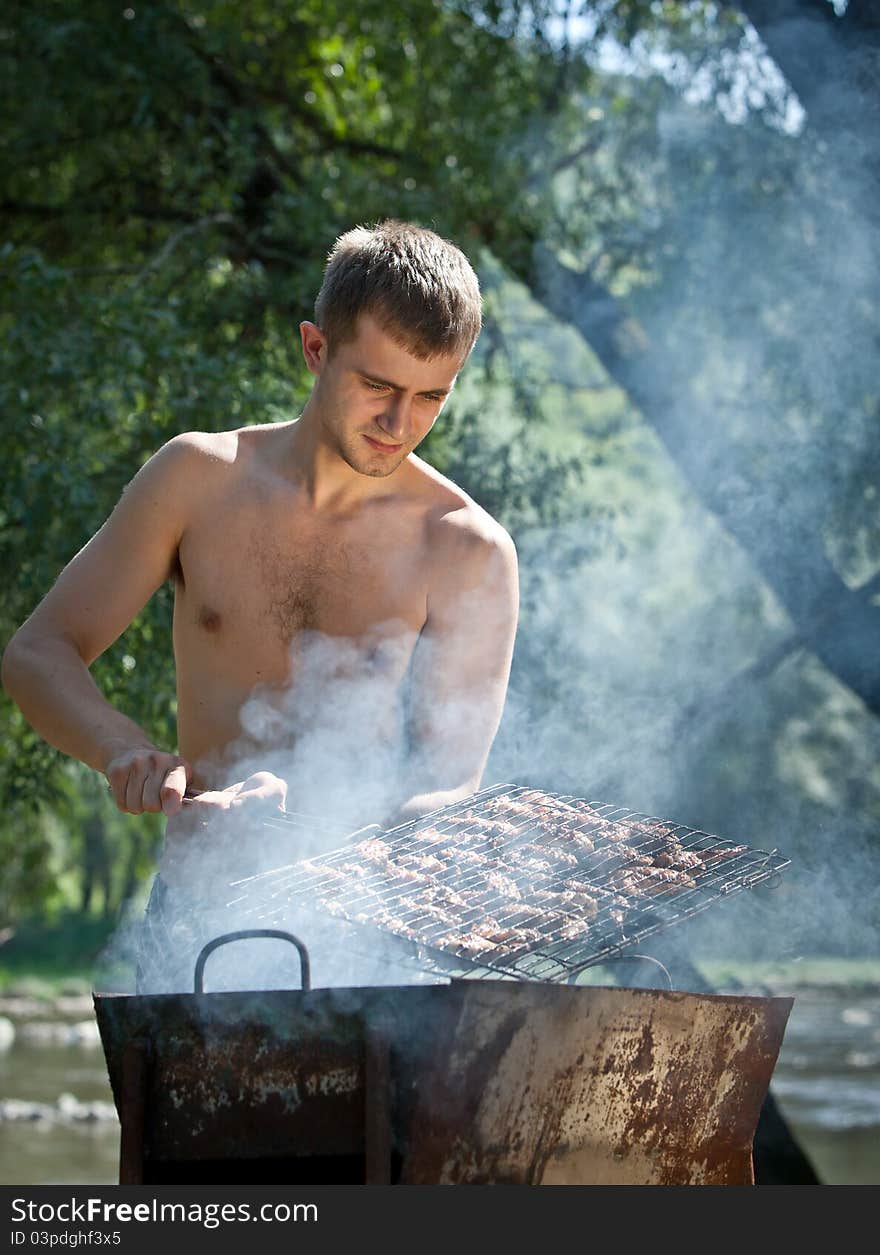 Young man preparing barbecue outdoors. Young man preparing barbecue outdoors