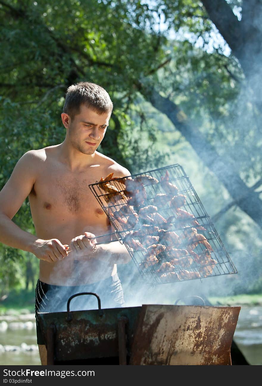 Young man preparing barbecue outdoors. Young man preparing barbecue outdoors