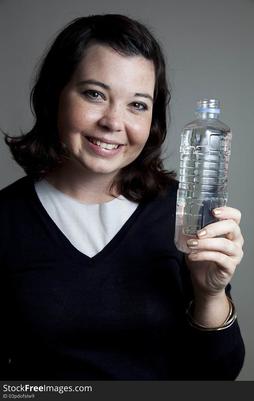 A young girl holding a water bottle with a big smile. A young girl holding a water bottle with a big smile.