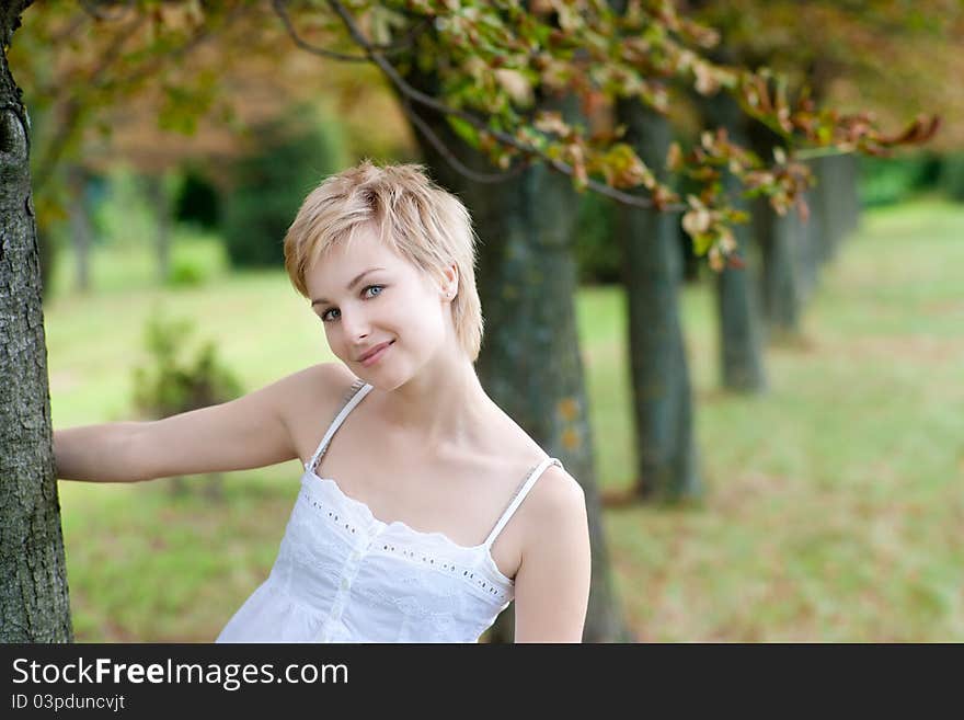 Portrait Of Young Smiling Woman Posing Near The Tr