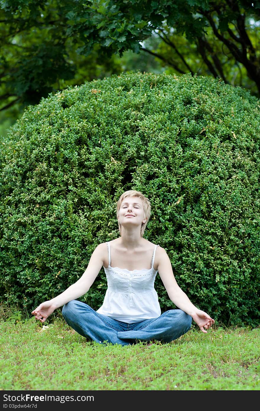 Image of meditating girl seated in pose of lotus on green grass. Image of meditating girl seated in pose of lotus on green grass