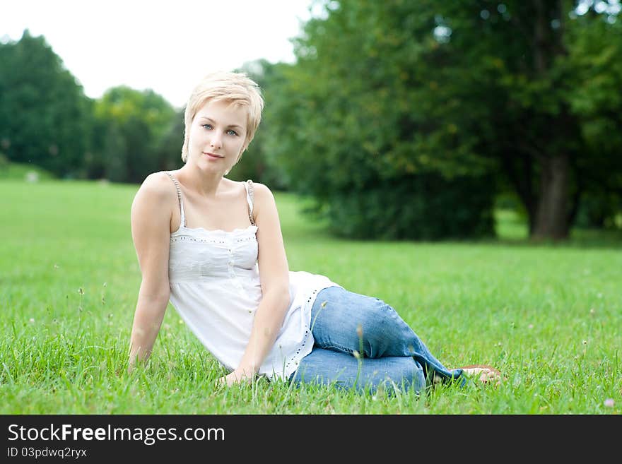 Portrait of beautiful young woman sitting on green grass on natural background. Portrait of beautiful young woman sitting on green grass on natural background