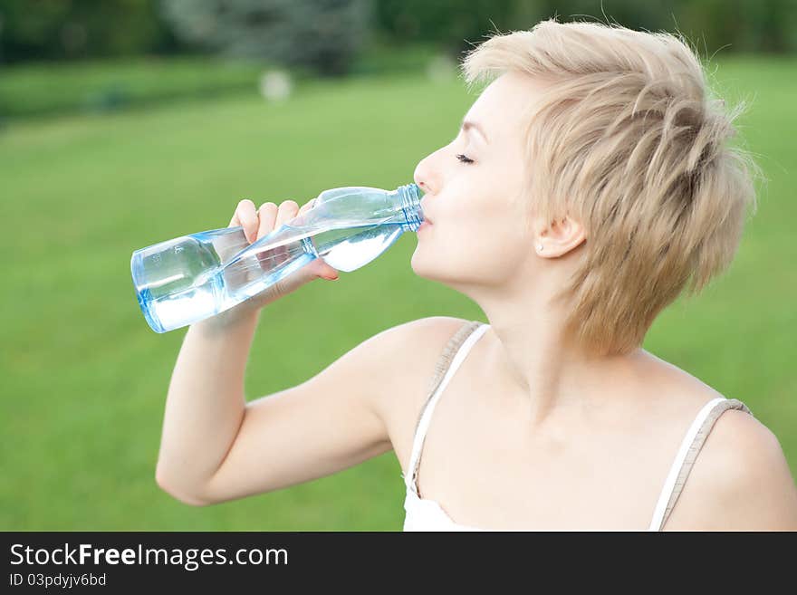 Young woman drinking water outdoors. Young woman drinking water outdoors