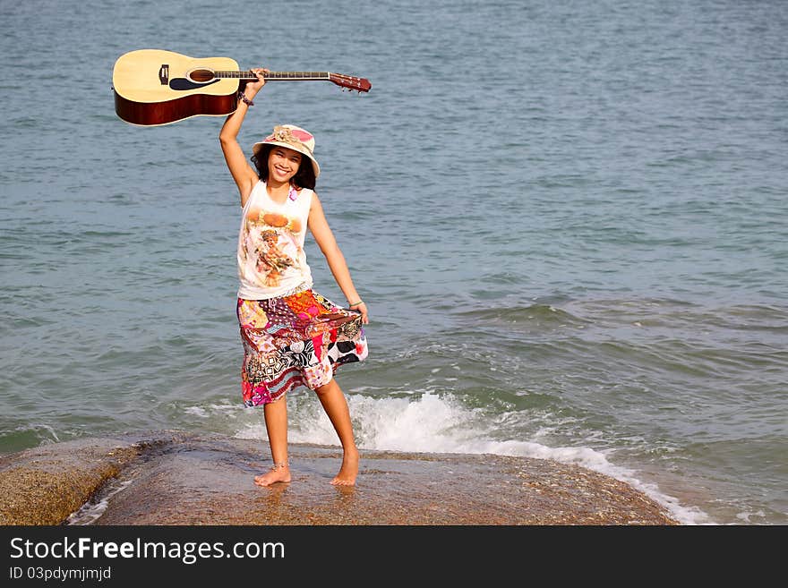 Pretty young woman with guitar on beach