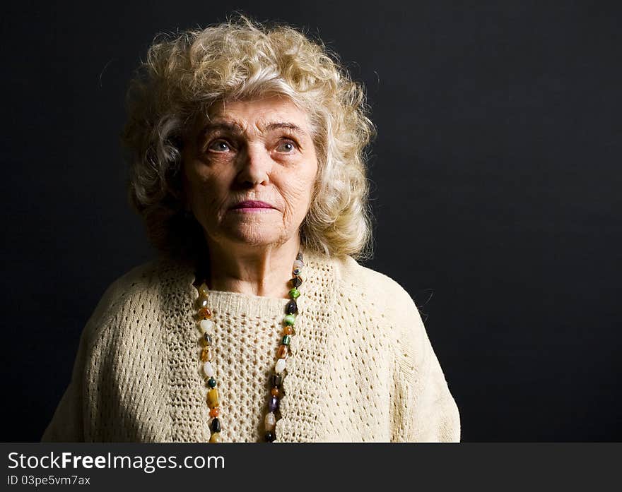 Portrait of woman in her eighties on black background. Portrait of woman in her eighties on black background