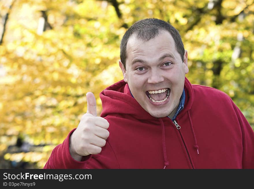 Very happy guy outdoors doing a positive sign. Thumbs Up.