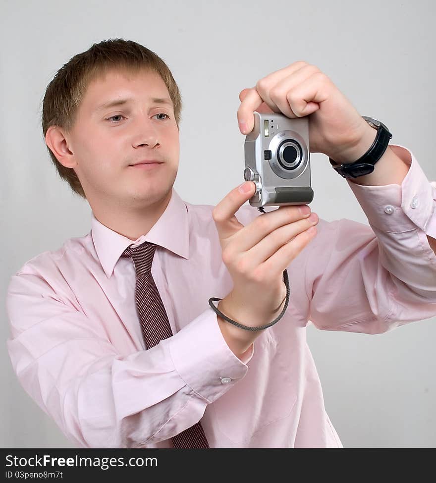 The young man photographed in studio, in a light shirt, with a tie, poses with the camera. The young man photographed in studio, in a light shirt, with a tie, poses with the camera