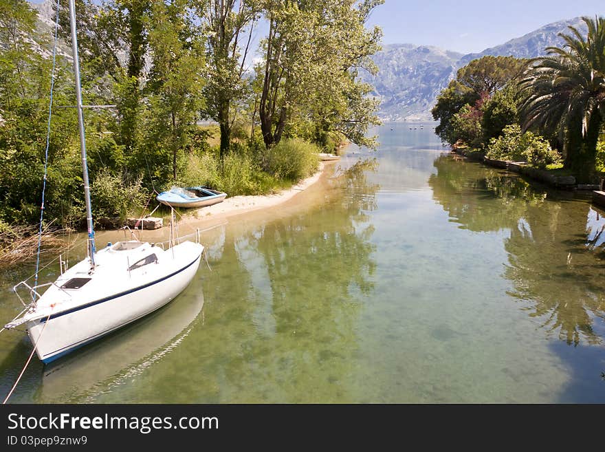 Small sailing boat on canal in Montenegro summer time. Small sailing boat on canal in Montenegro summer time.