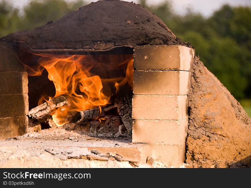 A hot fire burning in an earthen oven with a blackened top. The door is framed with bricks. A hot fire burning in an earthen oven with a blackened top. The door is framed with bricks.