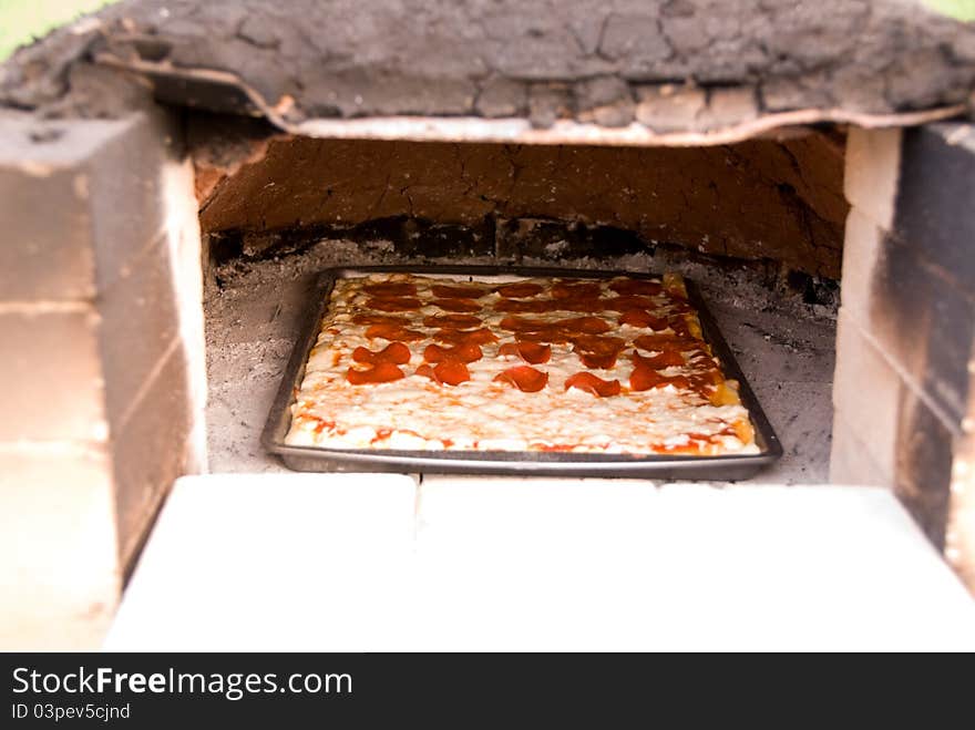 A pizza baking in an earthen oven. This is an old fashioned way of baking. A pizza baking in an earthen oven. This is an old fashioned way of baking.