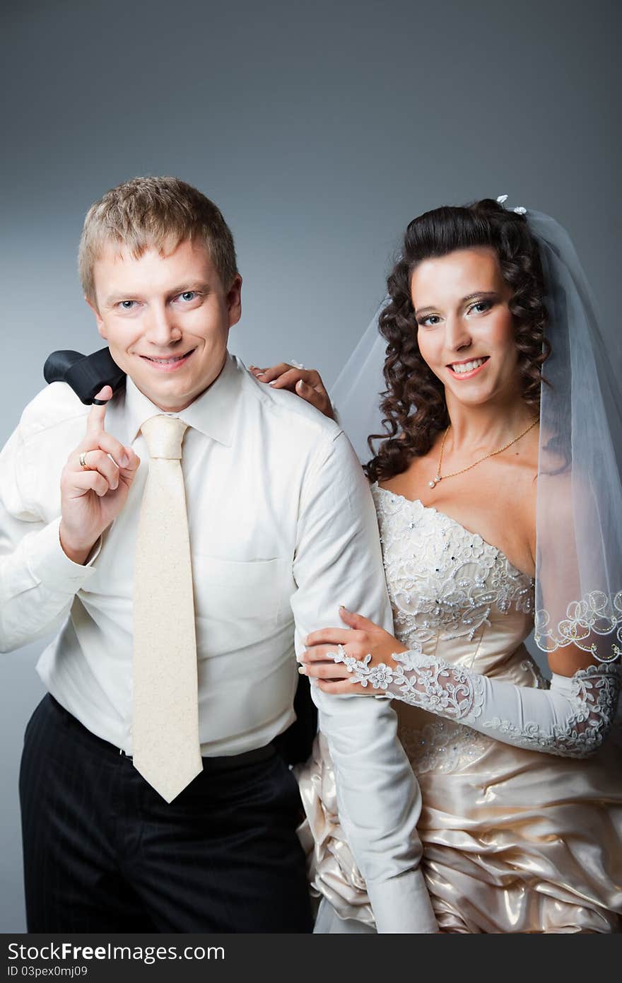 Studio portrait of young beautiful happy just married bride and groom embracing on blue background