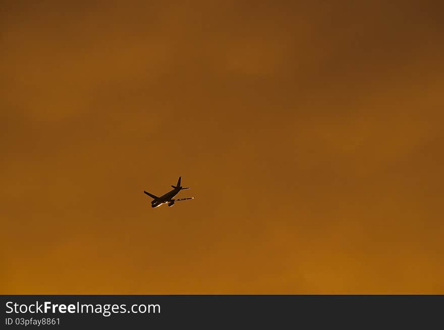 Airplane silhouette at sunset, cloudy sky