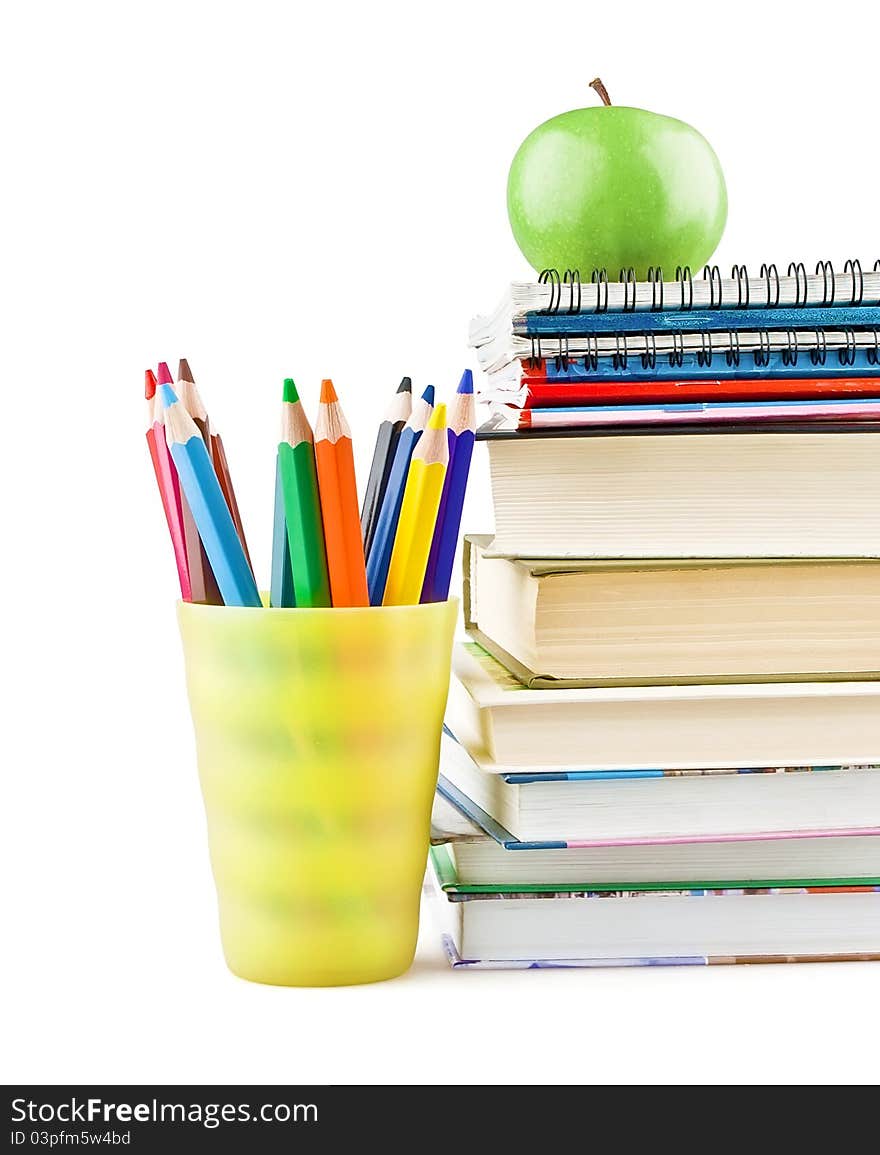 Textbooks and notebooks next to the pencils and green apple on top on white background. Textbooks and notebooks next to the pencils and green apple on top on white background