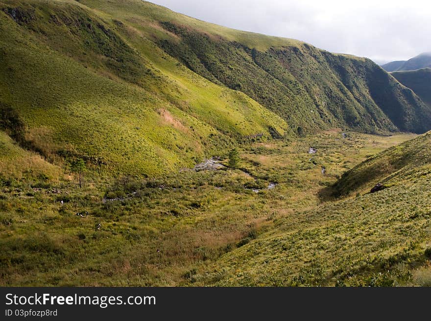 A group op people hiking next to a small stream in a large valley in south africa's drakensberg. A group op people hiking next to a small stream in a large valley in south africa's drakensberg