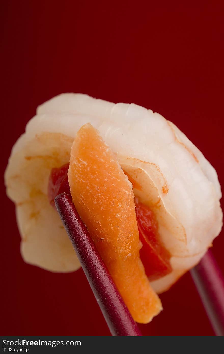 Shrimp from an appetizer in red chopsticks on a red background. Shrimp from an appetizer in red chopsticks on a red background.