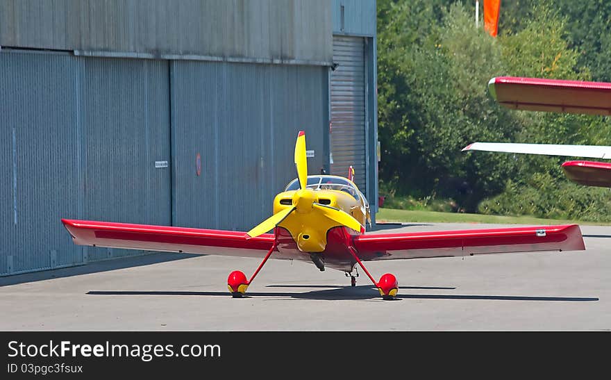 Small ariplane on the ground near hangar