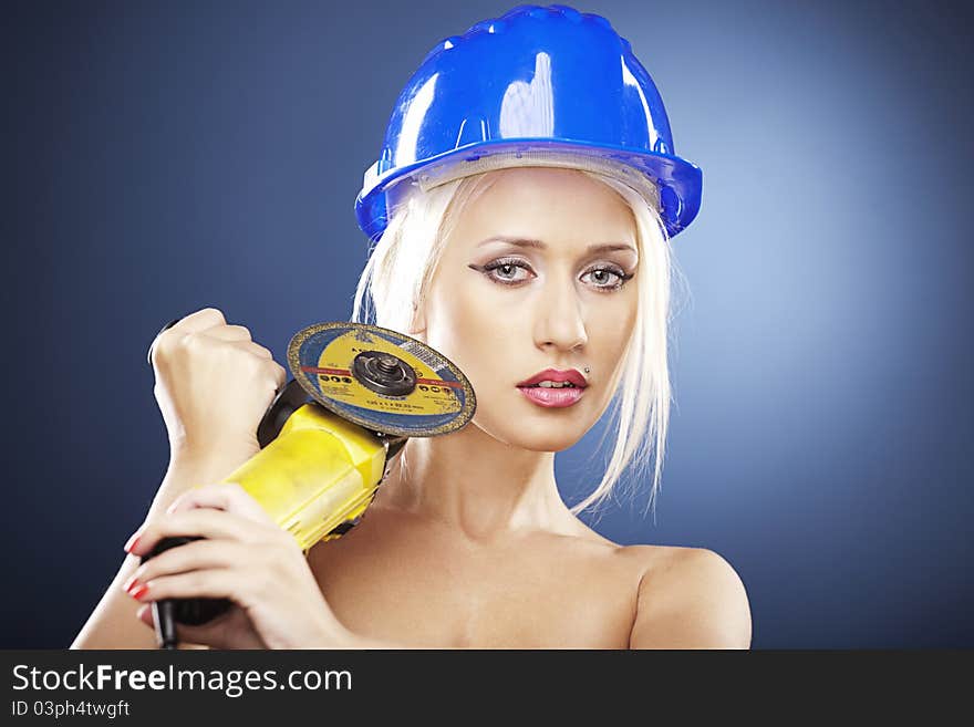 Beautiful topless model holds an angle grinder while wearing a blue construction helmet. Beautiful topless model holds an angle grinder while wearing a blue construction helmet.