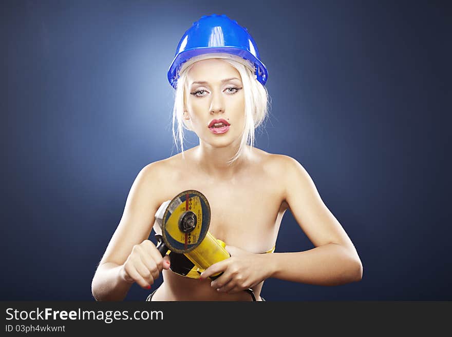 Beautiful topless model holds an angle grinder while wearing a blue construction helmet. Beautiful topless model holds an angle grinder while wearing a blue construction helmet.