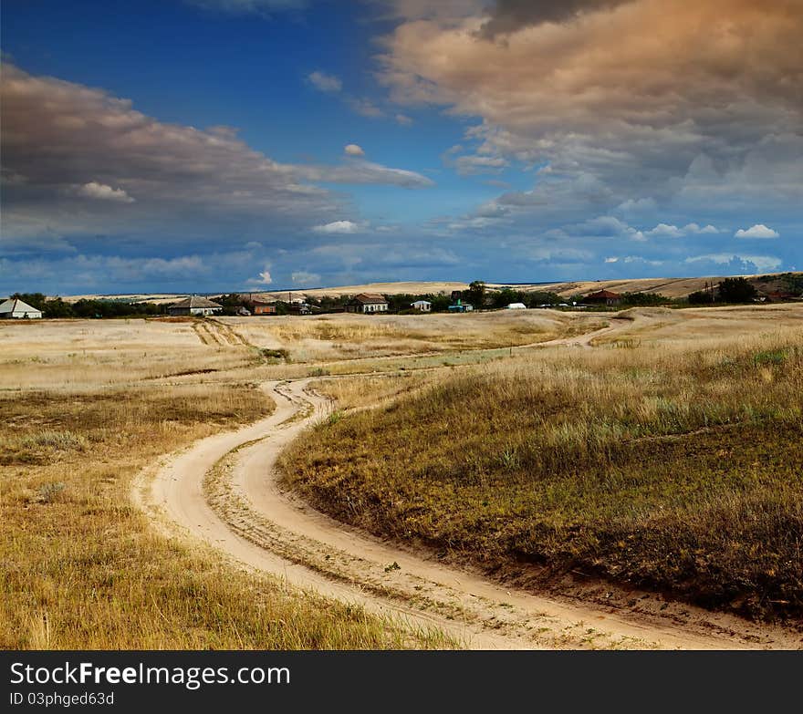 Road in field and stormy clouds