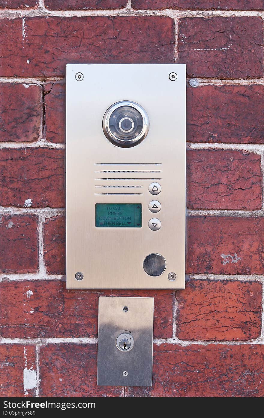 A metal security buzzer on a brick wall. A metal security buzzer on a brick wall