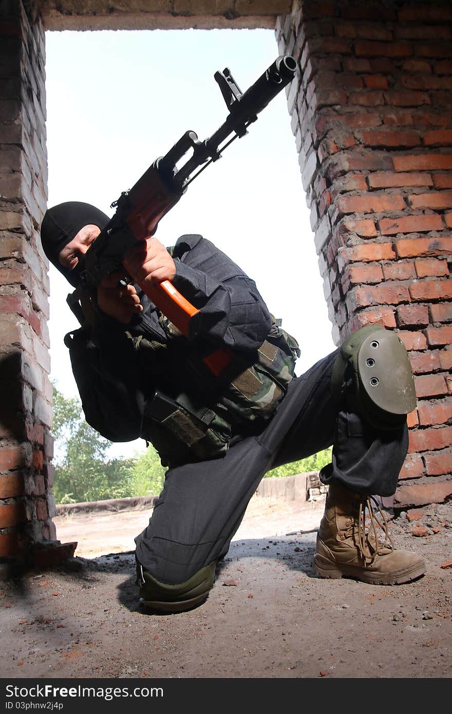 Armed soldier in black mask targeting with a gun