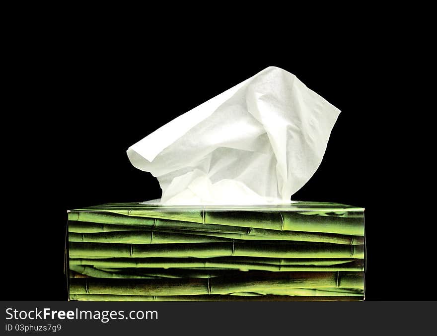 A green paper tissue box on a black background