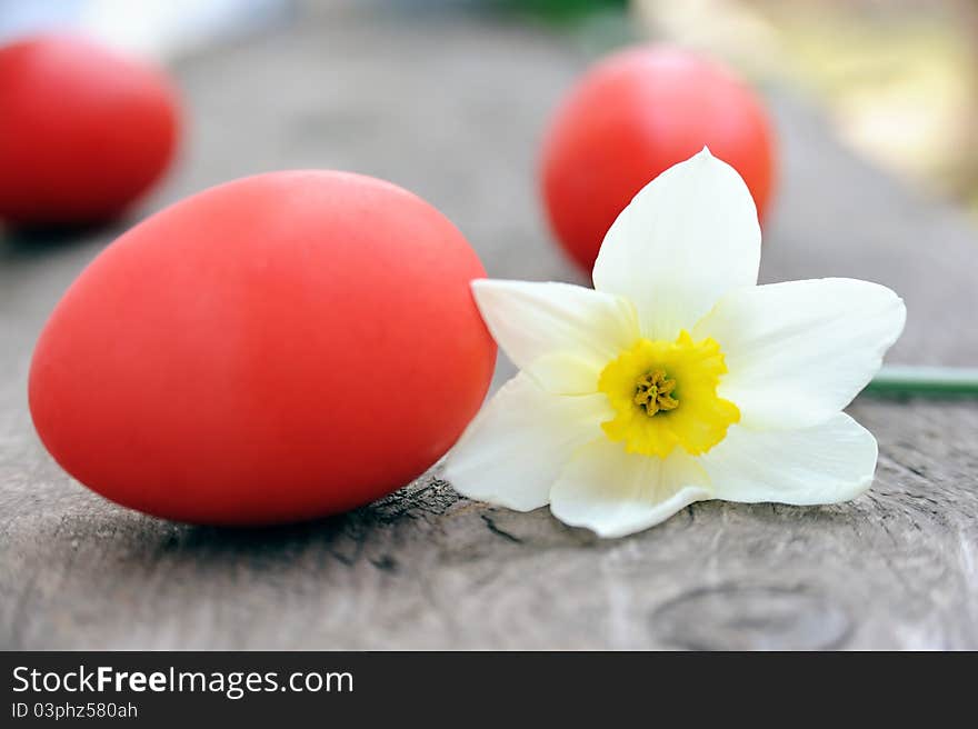 An image of three red eggs and a flower. An image of three red eggs and a flower