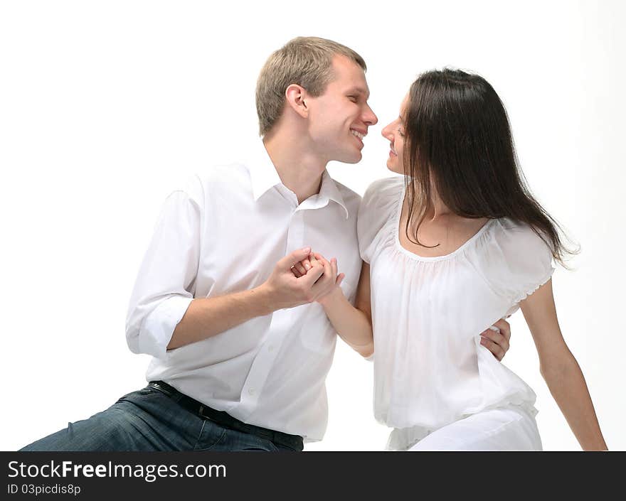 Couple in love: young man embracing young lady holding her hand; white background