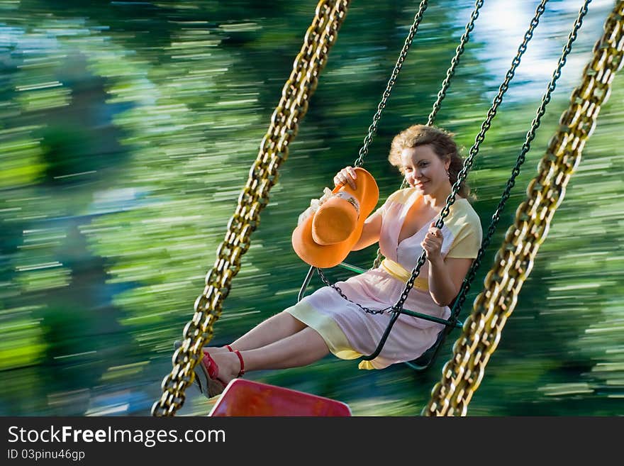 Beautiful young woman swinging and smiling. Image of swing blurred motion and happy girl at summer. Beautiful young woman swinging and smiling. Image of swing blurred motion and happy girl at summer.