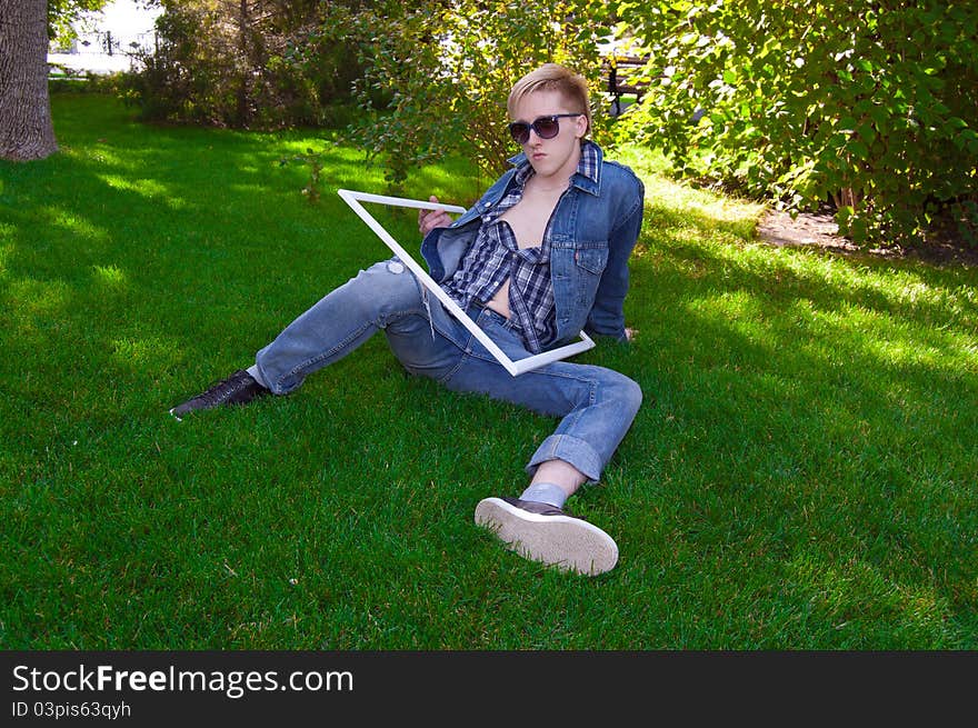 Young human on the green grass in white frame, he has blue goggles, jean jacket