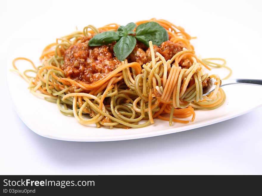 Spaghetti bolognese on a plate being eaten with a fork on white