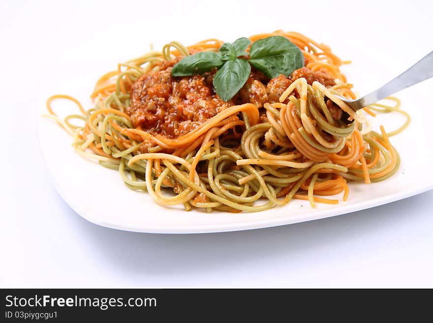 Spaghetti bolognese on a plate being eaten with a fork on white