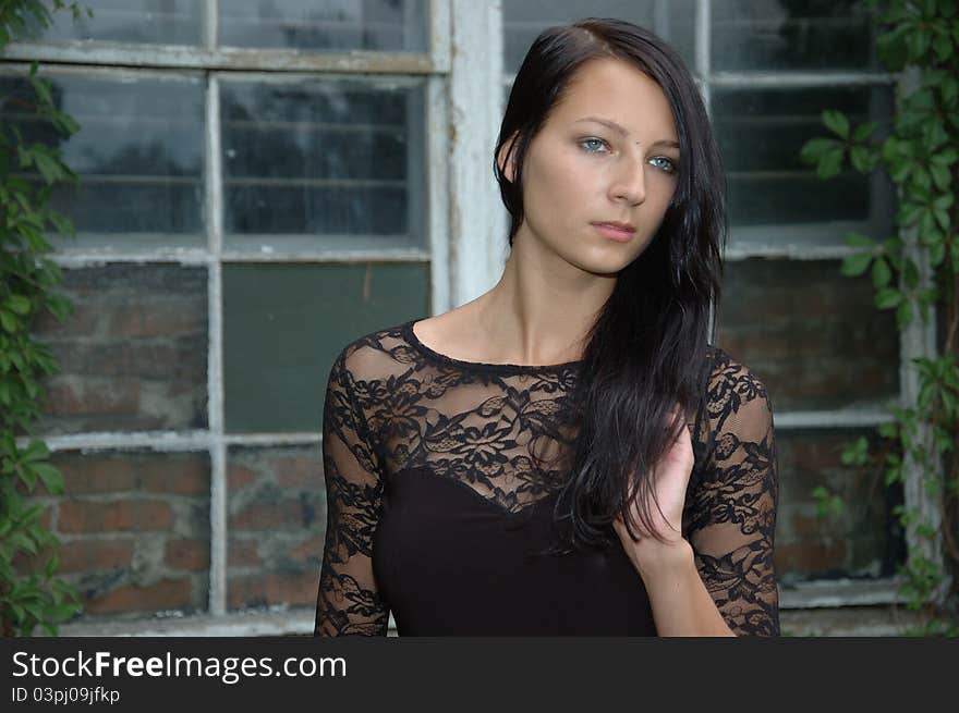 Portrait of young female model. Girl posing in front of old window, wearing black dress. Portrait of young female model. Girl posing in front of old window, wearing black dress.