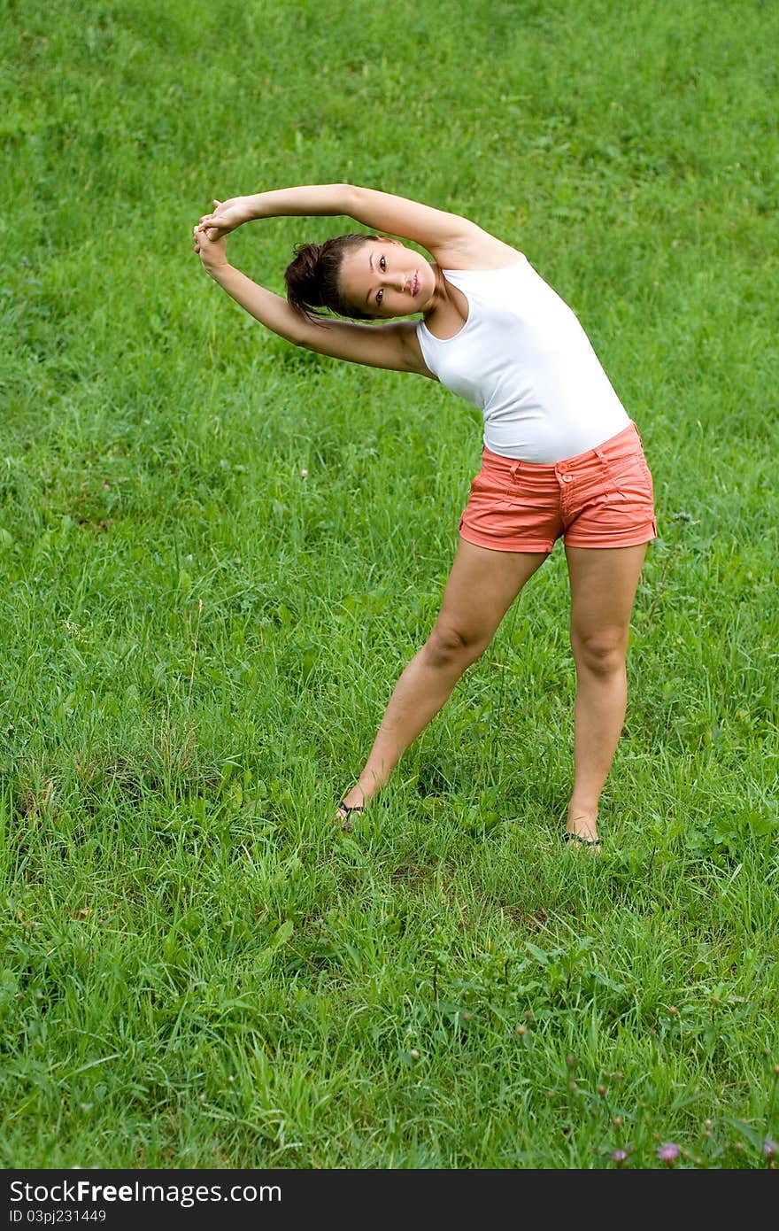 Girl doing exercises in park on grass