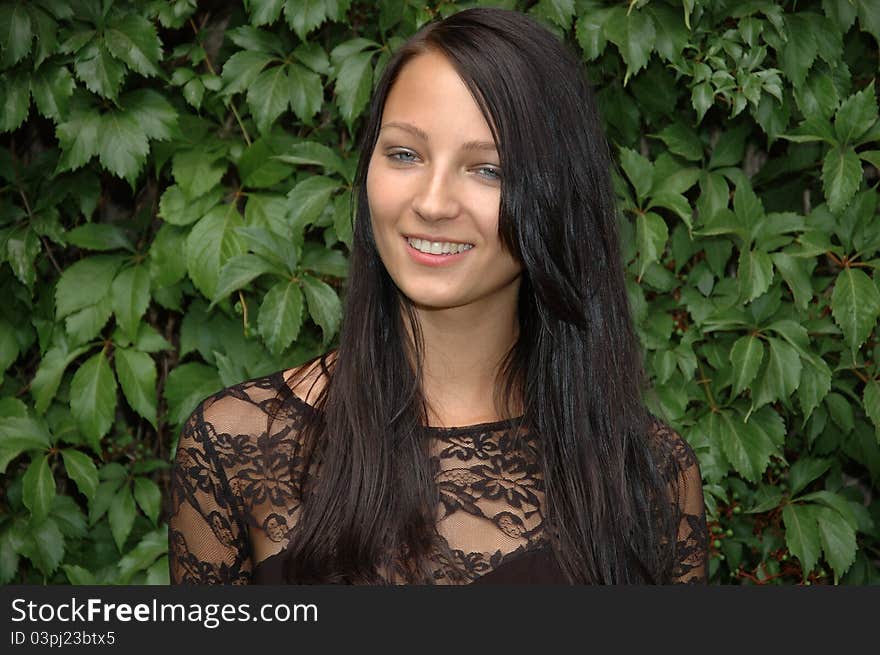 Charming female model from Poland, smiling. Young girl posing in garden with green leaves as background. Charming female model from Poland, smiling. Young girl posing in garden with green leaves as background.